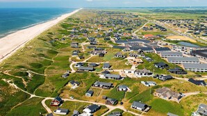 Vista aérea de una zona residencial costera con casas, una playa y una carretera.