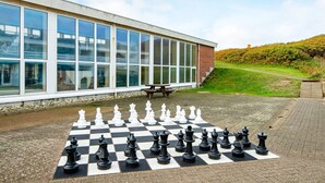 A chessboard set up on a paved area with a building in the background.
