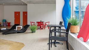 Un área de estar moderna con sillas rojas y negras, una mesita y una gran escultura azul.