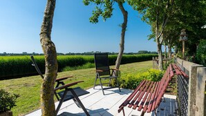 A patio with outdoor furniture, a view of a green field, and a clear sky. - Detached Chalet With a Panoramic View! (Goedereede)