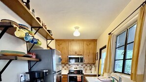 Una cocina compacta con armarios de madera, un refrigerador de acero inoxidable, un microondas, un horno y un lavamanos.
