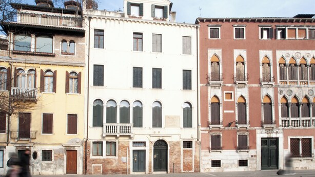 A row of historic buildings with varying architectural styles, including arched windows and balconies.