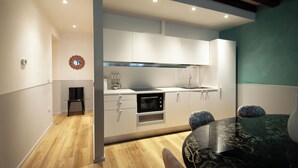 A modern kitchen with white cabinets, a black countertop, and a dining area with a black table and chairs.