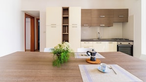 A modern kitchen with wooden cabinets, a gas stove, and a coffee maker on the table. - 3917 Villetta Giardino dei Pini by Barbarhouse (Alliste)