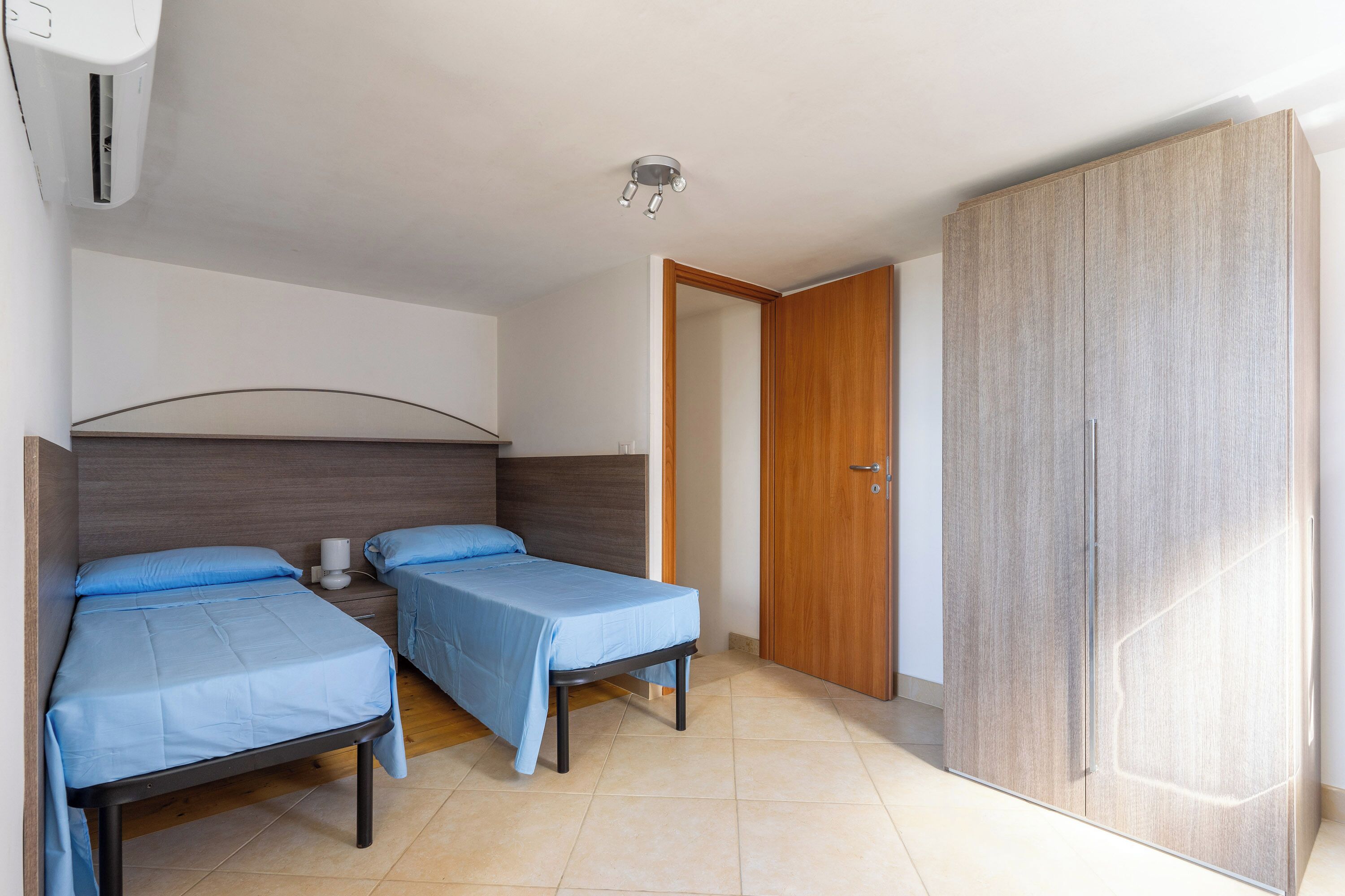 Ein Zimmer mit zwei Betten, einem Kleiderschrank und einer Deckenleuchte.