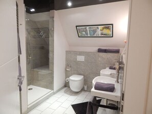 Een moderne badkamer met een glazen douchecabine, toilet en een wastafel met een handdoek.