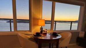 Ein Essbereich mit Tisch für zwei Personen, einer Lampe und Blick auf das Wasser.