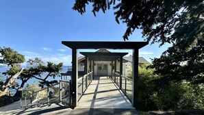 Ein überdachter Gang führt zu einem Gebäude mit Blick auf das Meer.