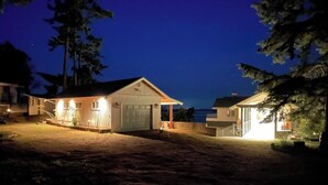 Een woonhuis met een garage, een overdekte veranda en een goed verlichte oprit 's nachts.