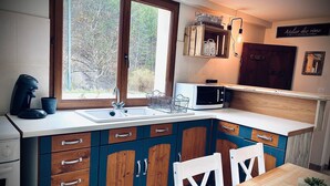 A kitchen with a sink, a microwave, and wooden cabinets. - Le Cottage du Brask (La Motte-du-Caire)