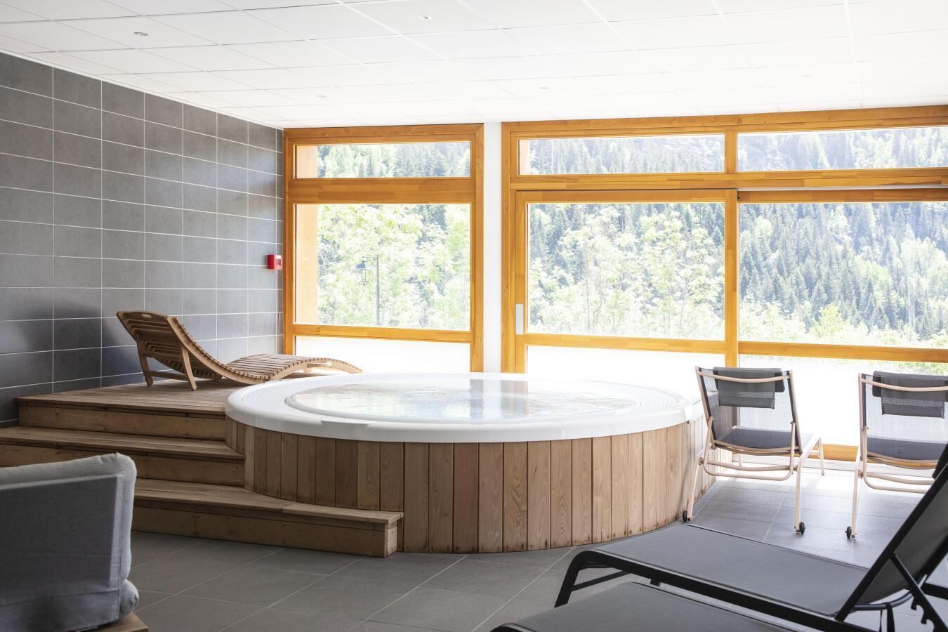 Wellnessbereich mit Whirlpool, Holzstufen und Sitzgelegenheiten.