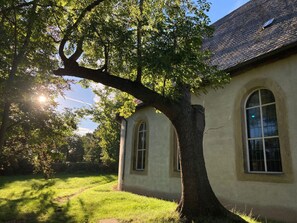 Un bâtiment doté de fenêtres en arc de cercle et d’un grand arbre devant.