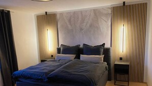 Un dormitorio moderno con una cama grande, dos mesitas de noche y un cabecero de madera con un diseño de hojas.