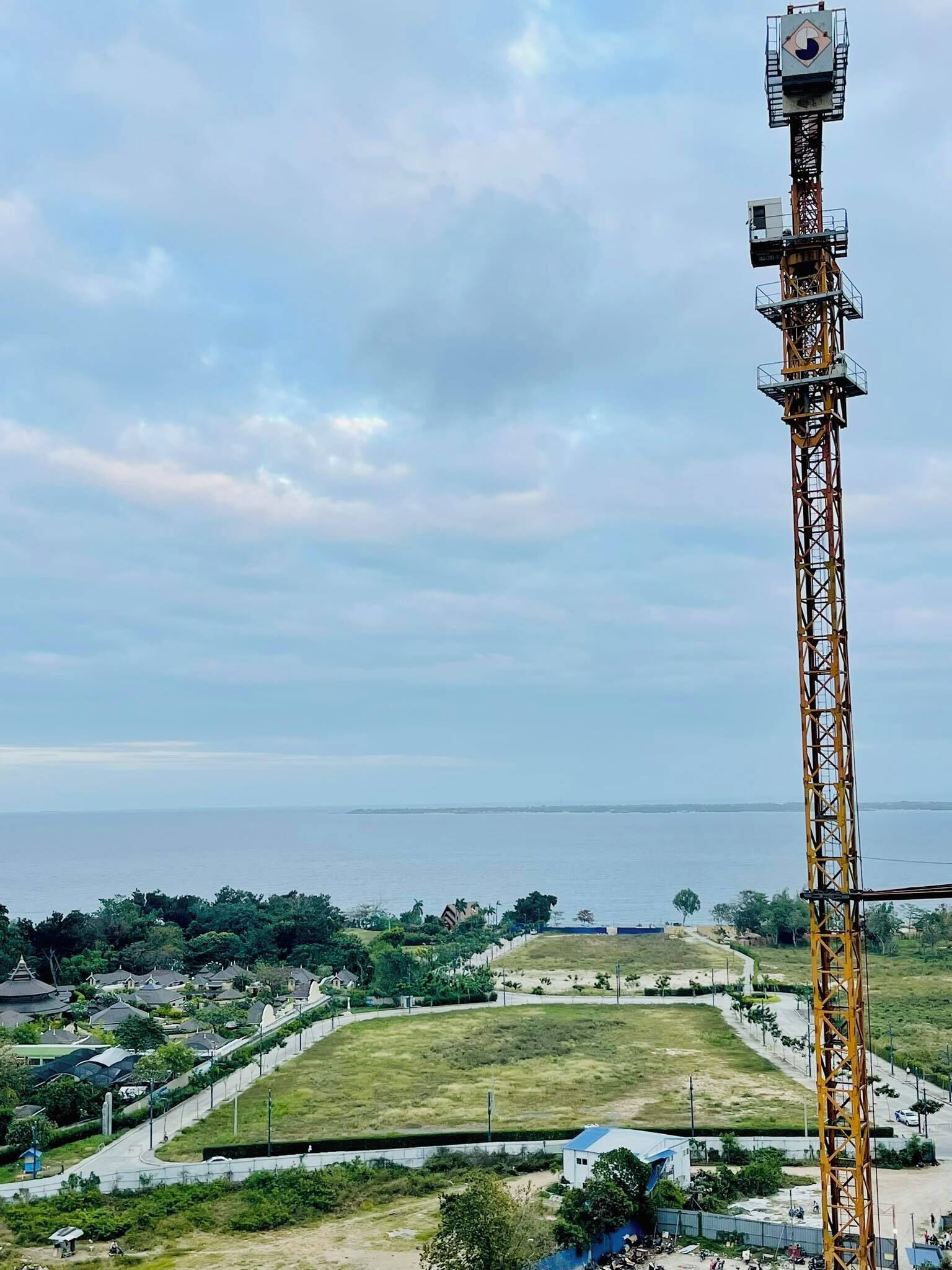 Ein hoher Sendeturm mit einem Kontrollraum auf der Spitze, der einen Küstenabschnitt mit Wohngebäuden und einer Straße überblickt.