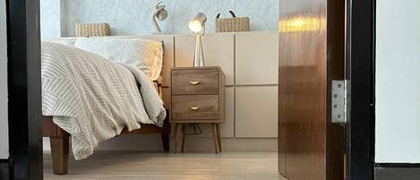 Un dormitorio moderno con cama, mesita de noche, lámpara y pared con diseño.