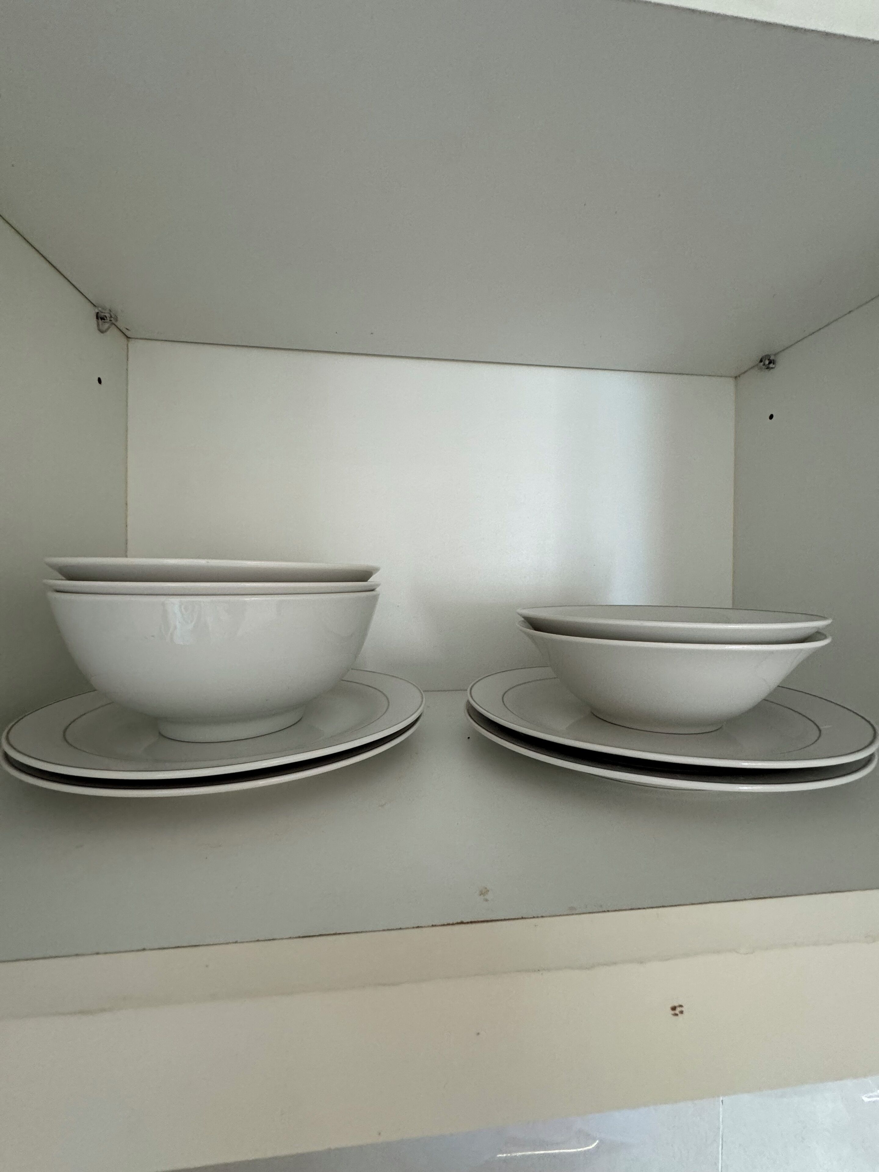 Dos tazones blancos sobre platos blancos, montados en una pared.
