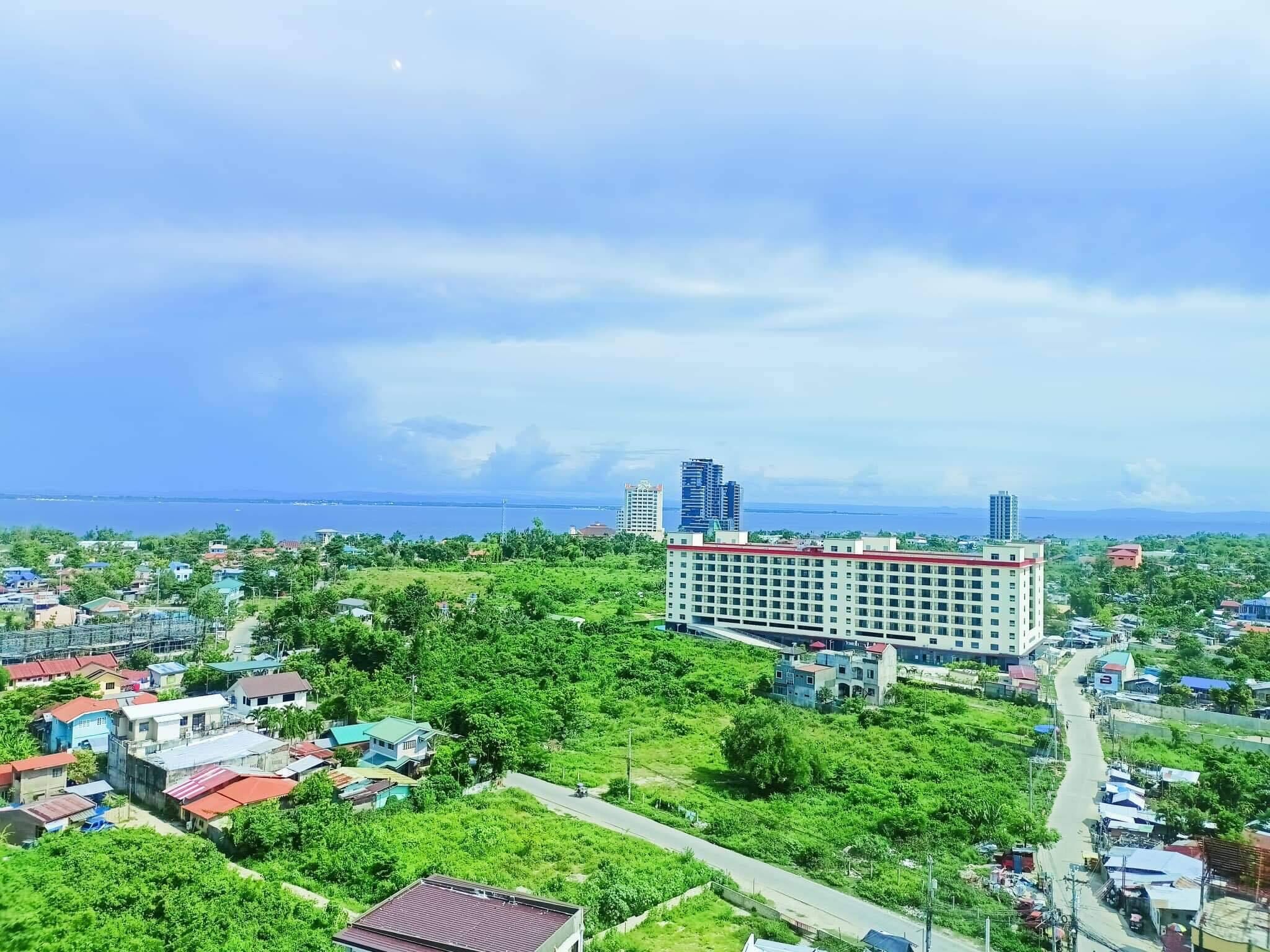 A large hotel with multiple floors and a red roof, surrounded by greenery and smaller buildings.
