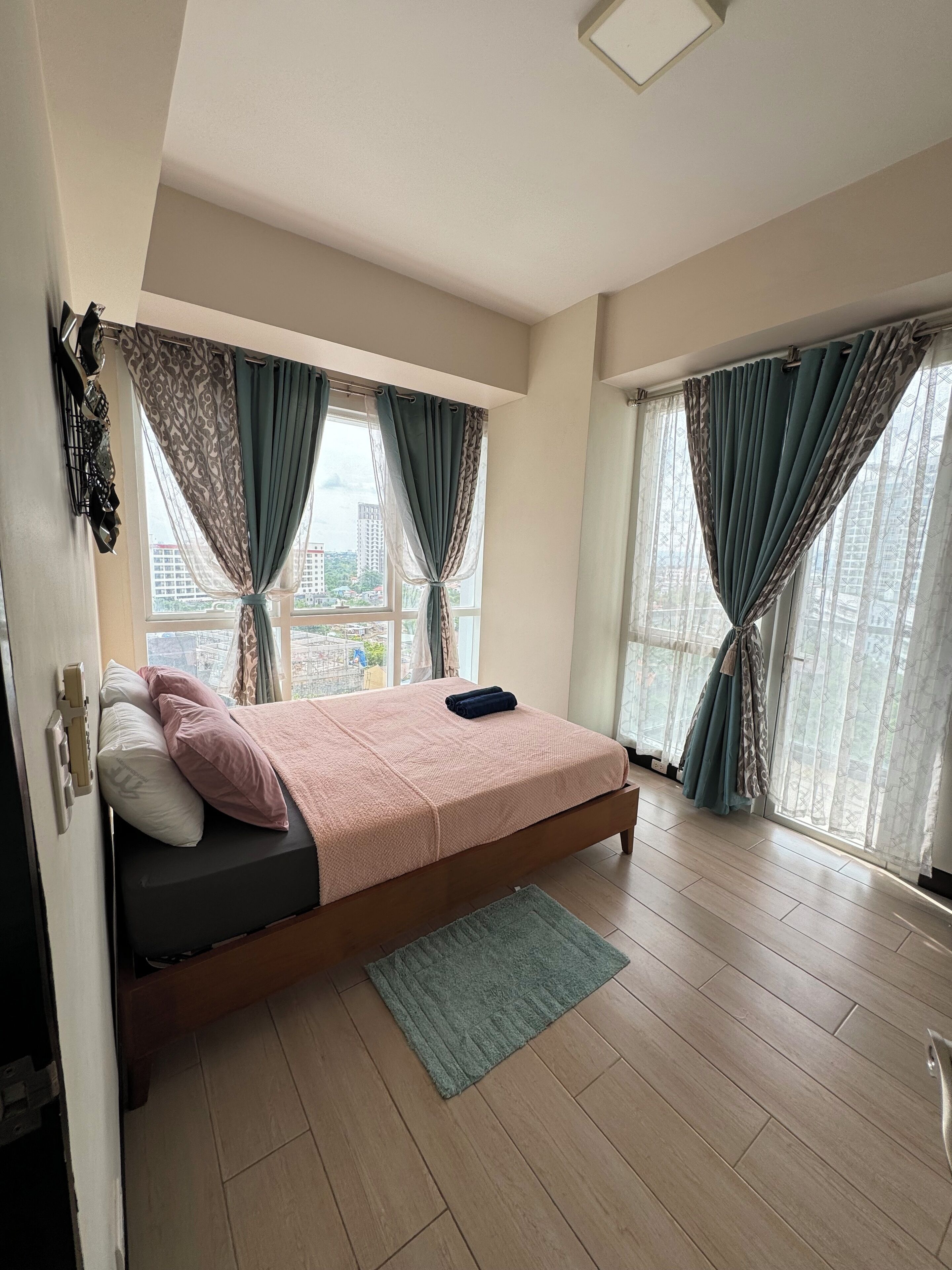 Un dormitorio con cama, cortinas, vista a la ciudad y ventana.