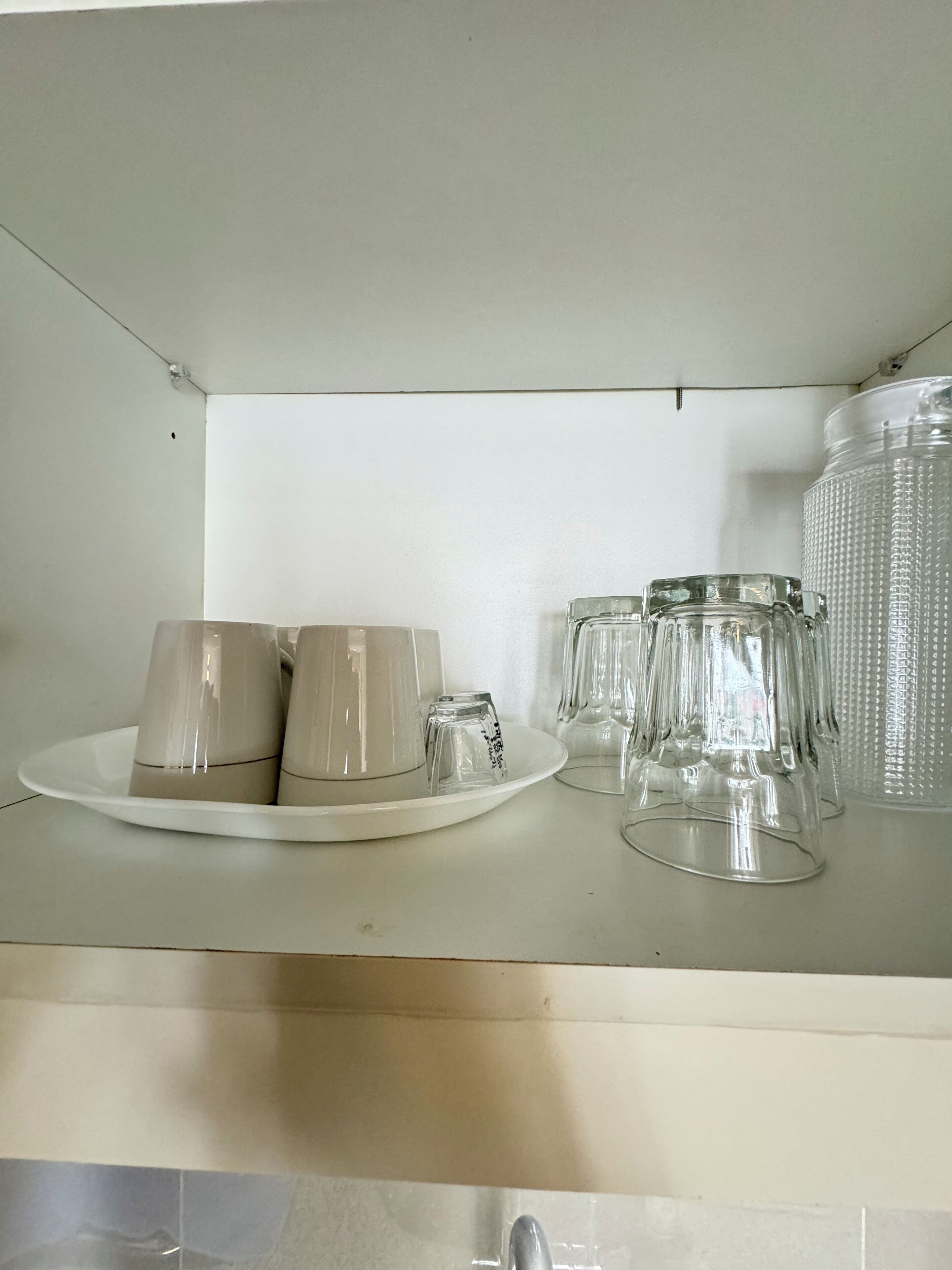 Un comptoir de cuisine sur lequel se trouve une assiette blanche contenant plusieurs verres et un bocal en verre.