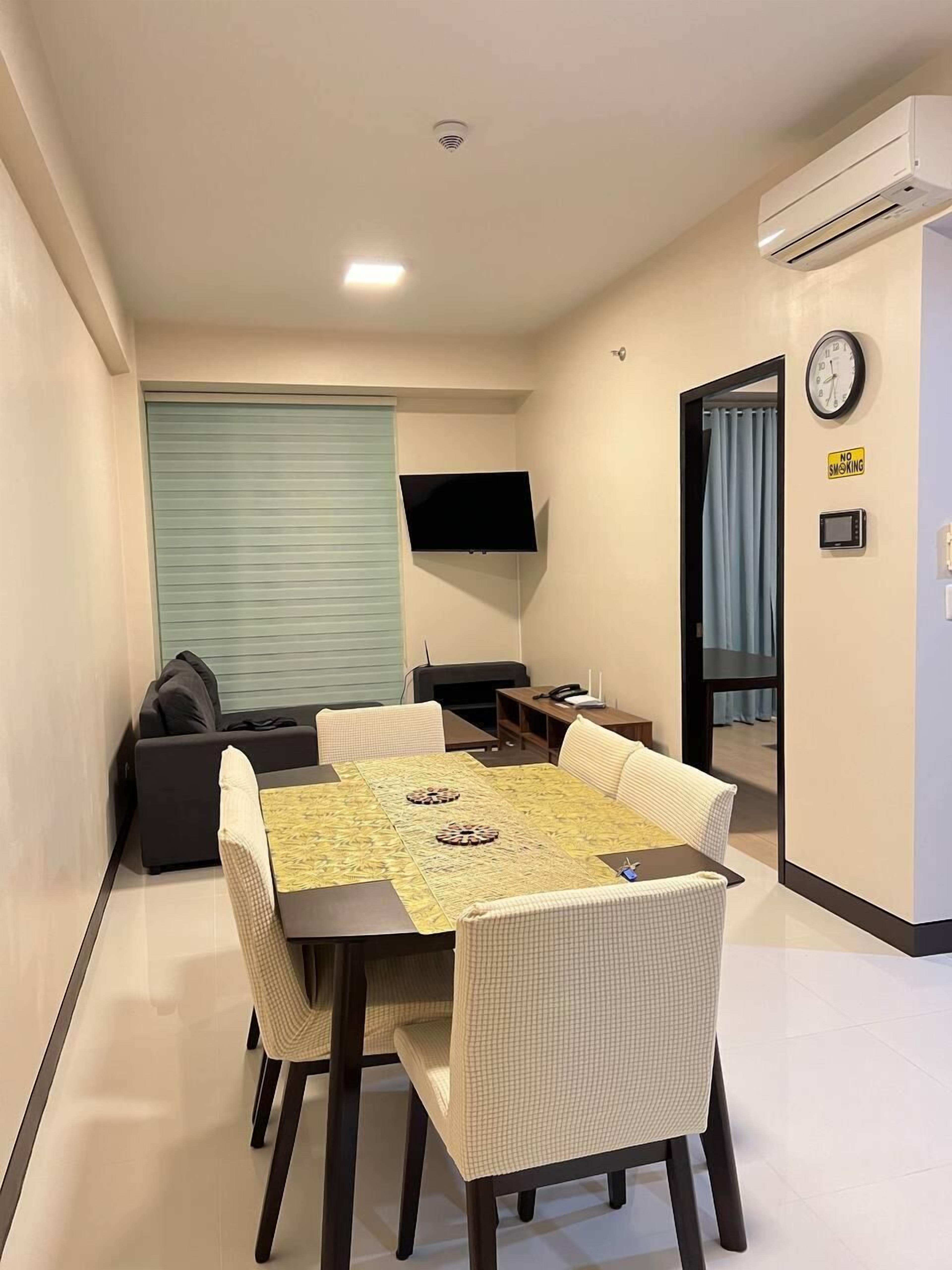 A compact living space with a dining area, a sofa, a TV, and a clock on the wall.