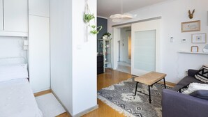 A modern living room with a sofa, a coffee table, and a patterned rug. There is a hallway leading to another room.