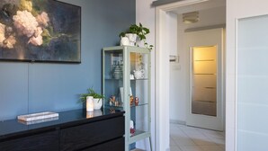 A modern interior with a dark wooden dresser, a glass cabinet with decorative items, and a painting on the wall.