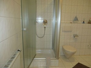 Un baño con ducha acristalada, inodoro y radiador.