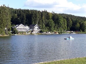 Un hotel junto al lago, con un edificio grande, rodeado de un bosque frondoso.