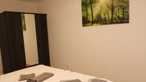 Une chambre avec un lit, un grand miroir et une décoration murale sur le thème de la forêt.