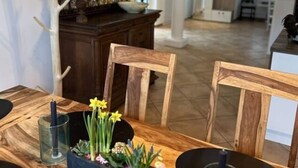 Un comedor con una mesa de madera, sillas y un centro de mesa con planta decorativa.