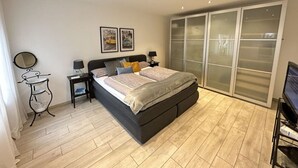 Un dormitorio con cama, mesitas de noche, espejo y armario.