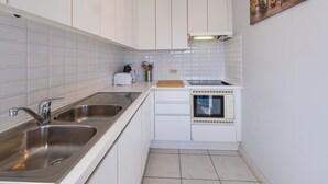A compact kitchen with white cabinets, a stainless steel sink, a microwave, and a toaster. - Apartment Overlooking the Green Surroundings (Middelkerke)