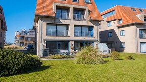 A modern multi-story residential building with a brick facade, large windows, and a sloped roof. - Apartment Overlooking the Green Surroundings (Middelkerke)