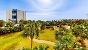 Ein Golfplatz mit Palmen, einem klaren Himmel und einem hohen Gebäude im Hintergrund.
