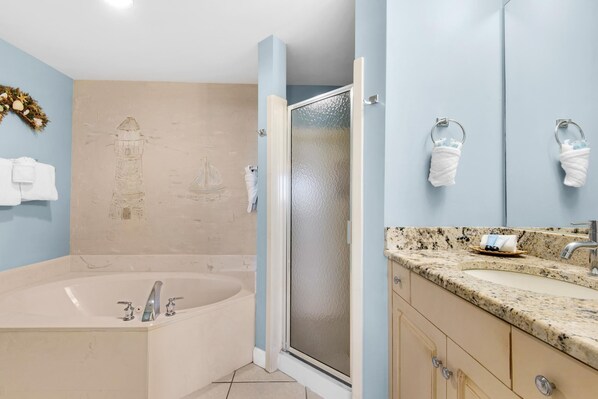 A bathroom with a bathtub, a shower, and a sink with a granite countertop.
