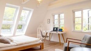 Ett modernt sovrum i loftstil med en säng placerad på ett loft, ett skrivbord och en stol.