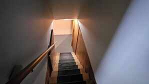 Een trap met houten treden en een leuning, leidend naar een plateau met een lichtbron.
