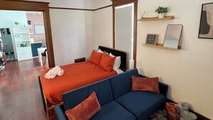 A bedroom with a bed, a blue sofa, a patterned rug, and a small plant on a shelf. - Downtown Studio: Close to CC (Colorado Springs)