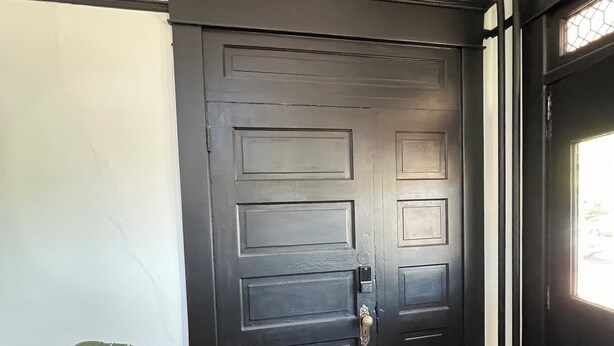 A dark wooden door with a modern handle, a potted plant, and a wooden floor with a black and white rug. - Downtown Studio: Close to CC (Colorado Springs)