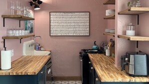 A kitchen with wooden countertops, a sink, and a stove. There are shelves with glassware and a framed picture on the wall. - Downtown Studio: Close to CC (Colorado Springs)