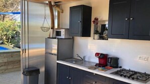 A compact kitchen with dark cabinets, a stainless steel refrigerator, a gas stove, and a coffee maker. - Atypical, set on the beach with direct access, swimming pool, barbecue, pets allowed (Marseillan)