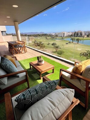 Un espacio de descanso moderno al aire libre, con vista a un campo de golf y una masa de agua.