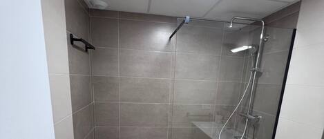 Een moderne badkamer met een douche, toilet en wastafel.