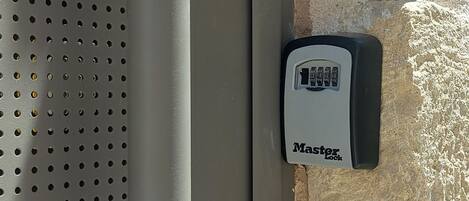 Ein Master Lock Vorhängeschloss auf einer Metalloberfläche mit einem gelochten Muster.