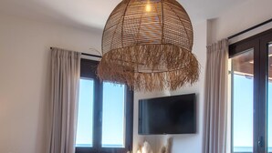 Quarto com cama, televisão na parede, janela e varanda com vista.