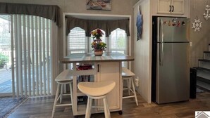 A kitchen with a central island, a refrigerator, and a window with curtains.
