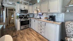 A modern kitchen with white cabinetry, stainless steel appliances, and a wooden floor.