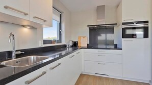 Een moderne keuken met witte kasten, roestvrijstalen apparatuur en een zwart aanrecht.