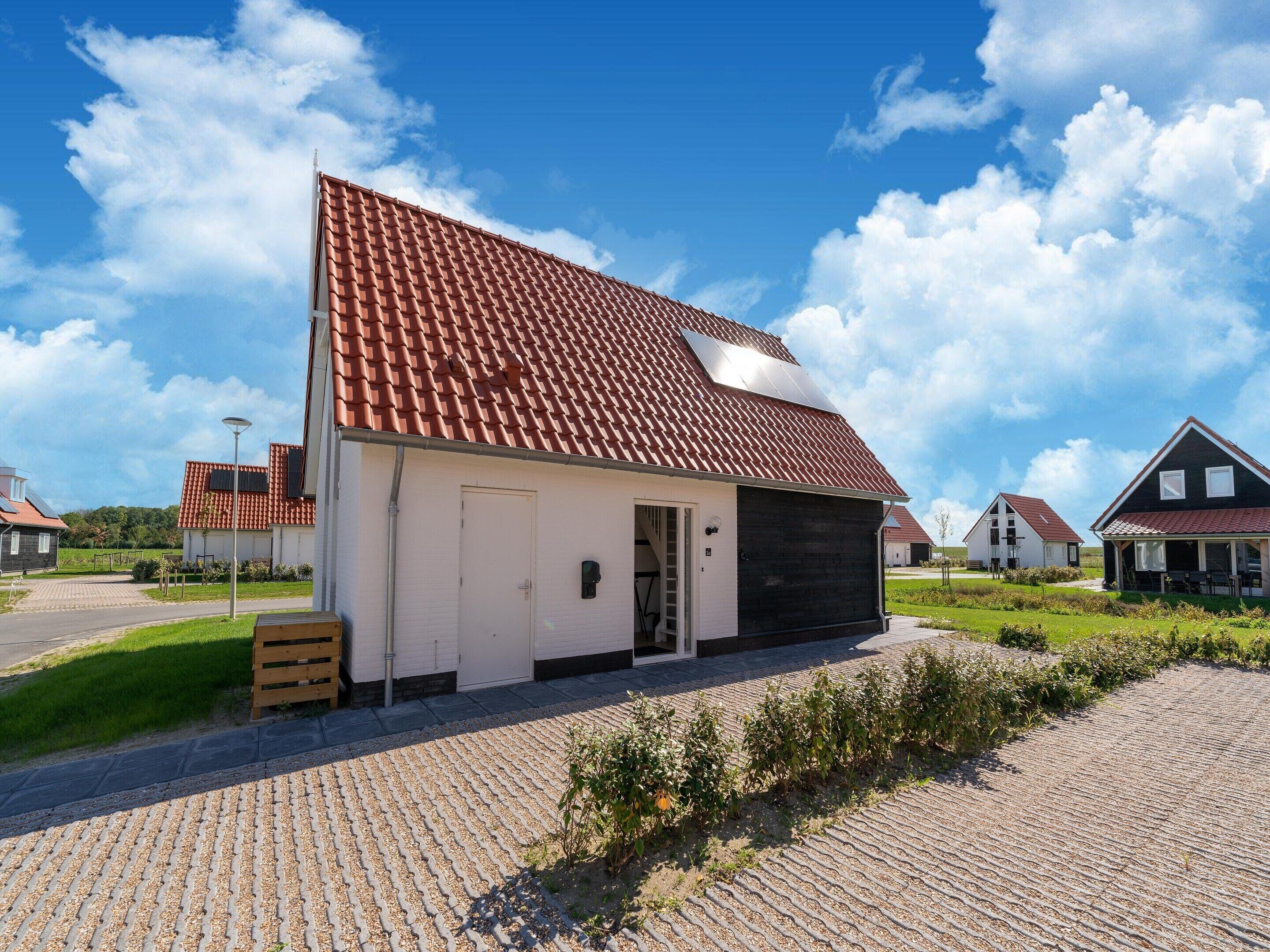 A single-story building with a red-tiled roof, a white exterior, and a black garage door.