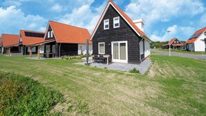 Een rij moderne huizen met rode pannendaken, een gazon en een heldere blauwe lucht.